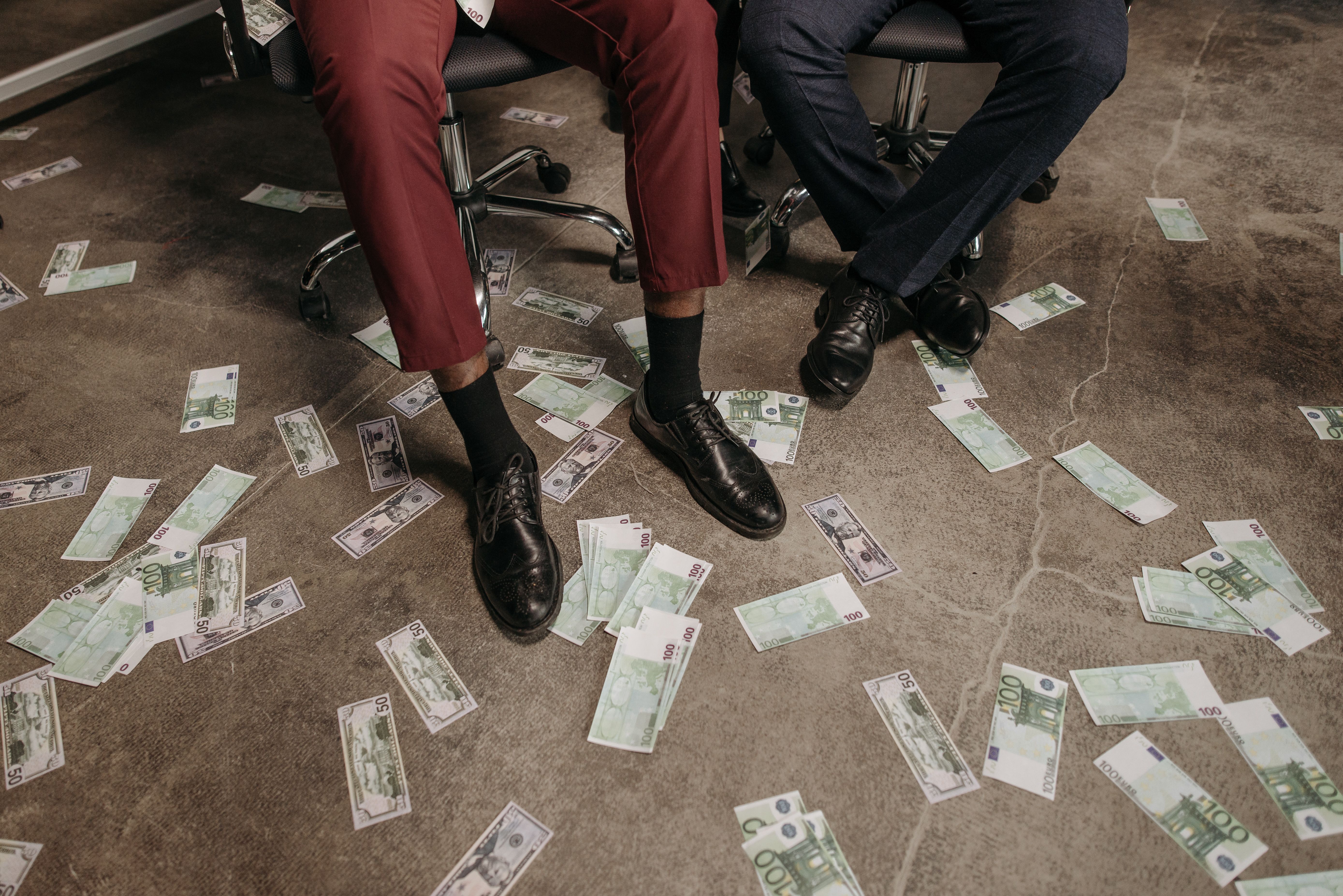 Two people in an office with euro banknotes scattered across the floor