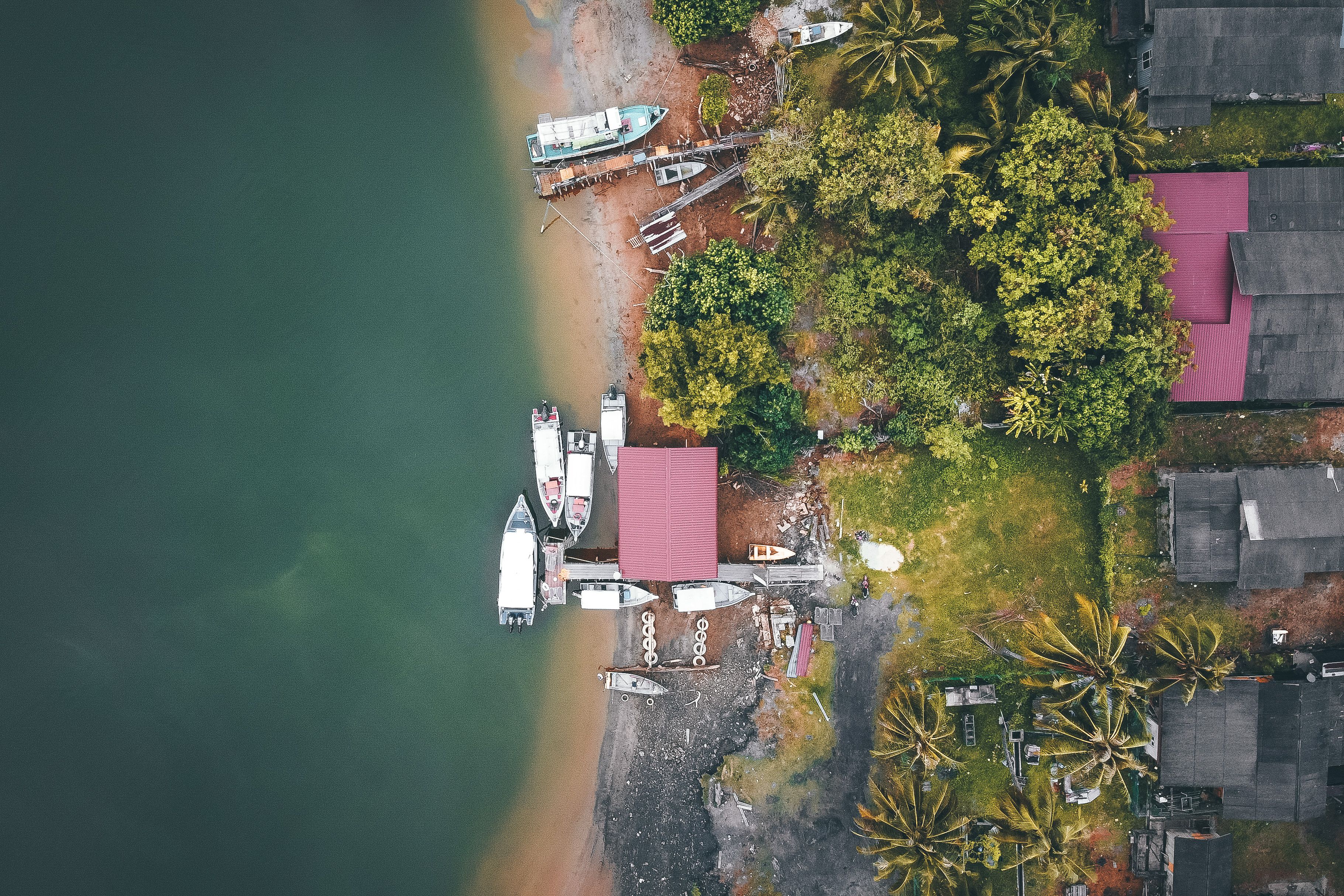 Boats and coastal homes along Sabah's tropical shoreline, illustrating coastal livelihoods and connectivity.