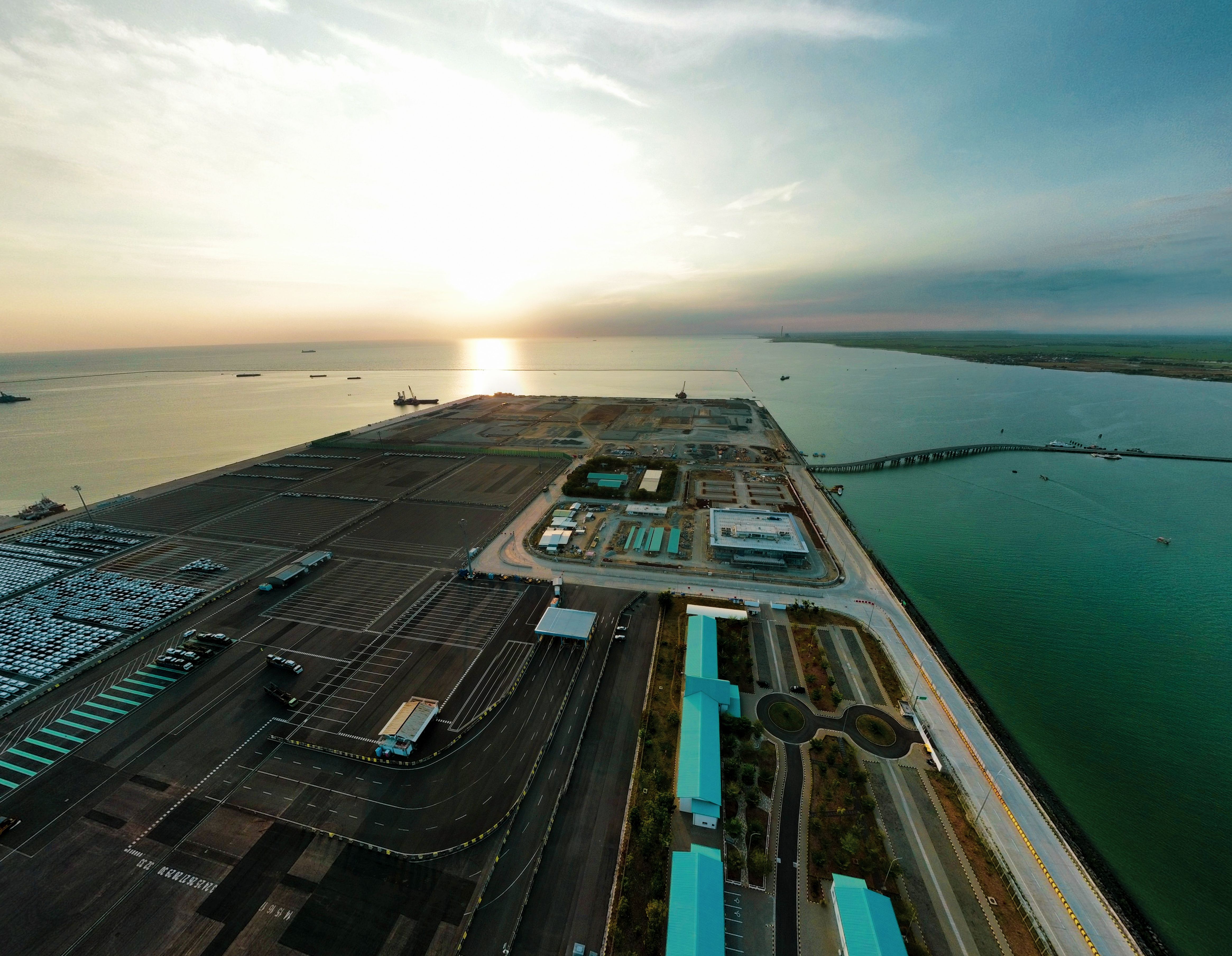 Aerial view of an industrial port and docks at sunrise, representing Sabah's maritime trade and logistics potential.